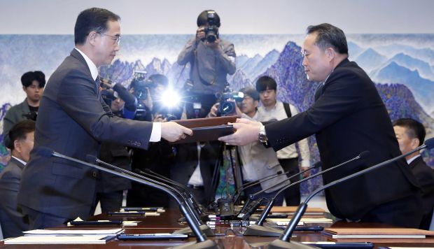 El ministro de Unificación surcoreano, Cho Myoung-gyon, y el presidente del Comité para la Reunificación Pacífica de Corea del Norte, Ri Son-gwon, intercambian documentos. (Foto: EFE)