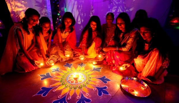 Un grupo de mujeres enciende velas sobre una flor Rangoli como decoración para el Diwali, o Festival de las Luces, en Bhopal, India. (Foto: EFE)