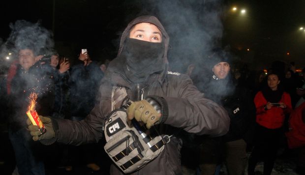 Un manifestante lanza una granada de humo contra el edificio durante su manifestación cerca de la embajada rusa en Kiev, Ucrania. (Foto: EFE)