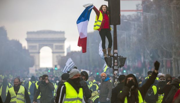 Una mujer grita consignas subida a un semáforo durante una protesta en los Campos Elíseos en París (Francia). (Foto: EFE)